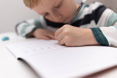 Okullu çocuk evde alfabe yazma alıştırması yapıyor. Çocuk çocuk yazıyor. Ev ödevi.