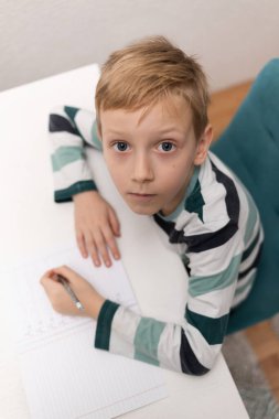 Okullu çocuk evde alfabe yazma alıştırması yapıyor. Çocuk çocuk yazıyor. Ev ödevi.