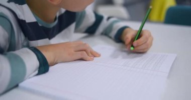 Okullu çocuk evde alfabe yazma alıştırması yapıyor. Çocuk çocuk yazıyor. Ev ödevi.