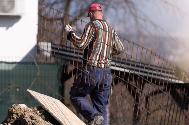 İnşaat işçileri inşaat alanında çelik takviye çubuğu üretiyorlar.