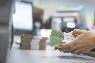 Large amounts of money in the bank. Bank employees sorting and counting money inside bank vault.