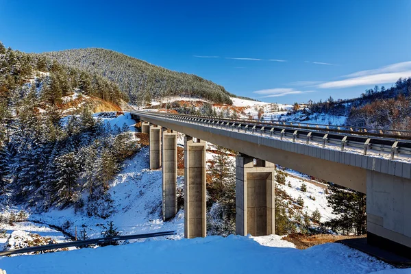 Mountain bridge in winter with snow and blue sky — Stock Photo, Image