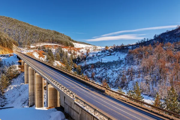 Mountain bridge in winter with snow and blue sky — Stock Photo, Image