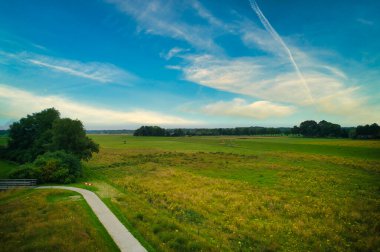 Vecht nehri yakınlarındaki doğaya drone bakış açısı, yeşil çimenler, ağaçlar, güzel mavi gökyüzü ve Dalfsen Hollanda, Vechtdal boyunca bisiklet yolu..