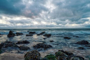 Manzara, Hollanda, Huisduinen sahilinde deniz manzaralı günbatımı. Uzun dalgaları ortaya çıkaran, dramatik gökyüzü, detaylı, yosun, kayalar