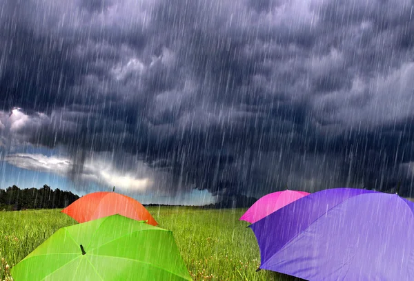 Guarda-chuvas coloridos em nuvens de tempestade chuvosa — Fotografia de Stock