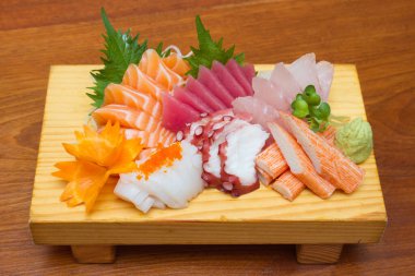 Sashimi (Japon yemeği). Tahta tabakta dilimlenmiş çiğ deniz ürünleri..