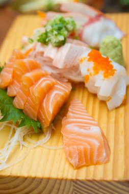Sashimi (Japon yemeği). Tahta tabakta dilimlenmiş çiğ deniz ürünleri..