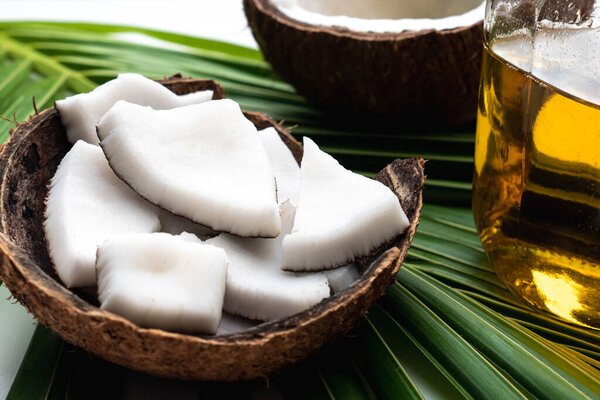 Coconut meat and coconut oil in glass bottle on coconut leaf.