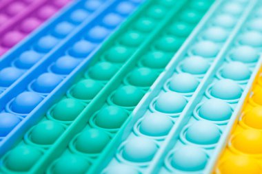 Popüler POP IT oyuncakları temasının bulanık renk arkaplanı. Tasarım elemanı. Silikon oyuncak yüzeyi, perspektif, dağılmış. Boşluğu kopyala.