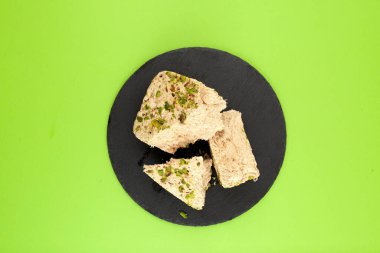 Bitki bazlı şam fıstığı Halva siyah taşın üzerinde. Doğulu tatlılar. Yeşil arkaplan, kopyalama alanı.