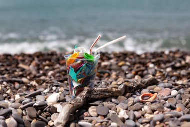 Tek kullanımlık plastik bardak ve deniz kenarında plastik çöp. Seçici odaklanma. Ekolojik sorunlar, deniz ve dünya okyanusu için tehdit.