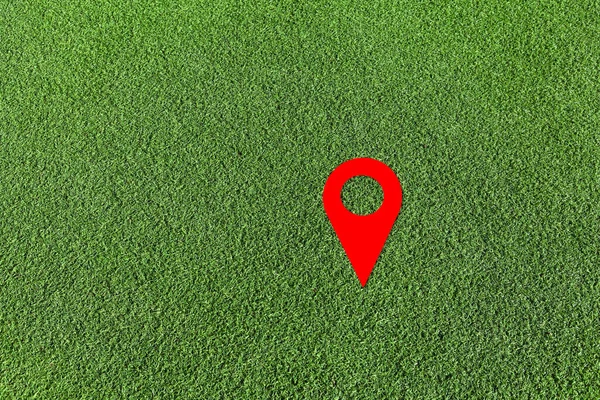 Red geo locate symbol on green lawn. Design element. Artificial green grass. Empty space.