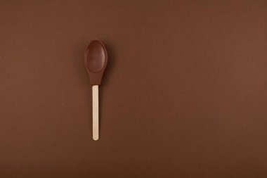 Kahverengi arka planda sütlü çikolata kaşığı ve fotokopi alanı. Tasarım elemanı. Yenilebilir milkshake kaşığı.