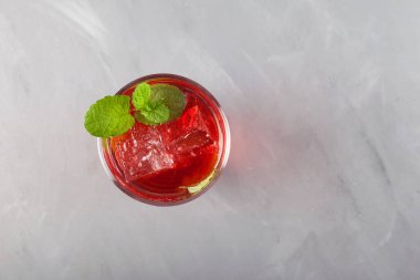 Yaz için renkli ferahlatıcı bir içecek, üst manzara. Naneli kırmızı meyve limonatası. Gri arkaplan, kopyala.