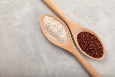 Ragi ya da Nachni, gri arka planda tahta kaşıklarda parmak darı ve ragi unu olarak da bilinir. Glütensiz sağlıklı yiyecek..