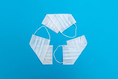 Geri dönüşüm sembolü yüz maskelerinden yapılır. Konsept - tıbbi çöp. Covid-19 koronavirüs salgınından kaynaklanan atık imhası sorunu. Çevre koruma.