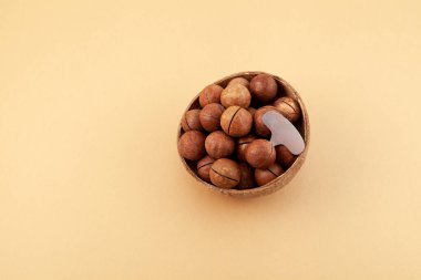 Fındık ezmesi ve metal anahtar bej arka planda fındık kabuğunu kasede açmak için. Besleyici, lezzetli ve sağlıklı atıştırmalıklar. Macadamia sert kabuklu lezzetli bir cevizdir..