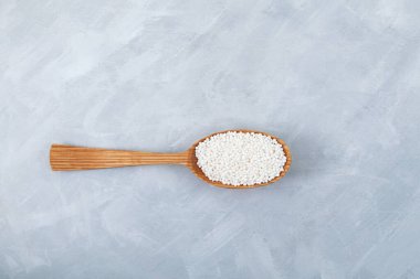 Beyaz tapyoka incileri gri arka planda tahta kaşıkta. Tapyoka topları ya da sago topları balonlu çay, boba içecekleri ve içecek kokteylleri için kullanılır..