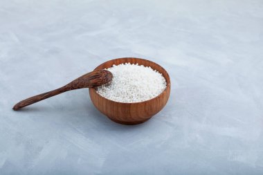 Tahta kasede beyaz tapyoka incileri ve ahşap kaşık. Tapyoka topları balonlu çay, boba içecekleri ve içecek kokteylleri için kullanılır..