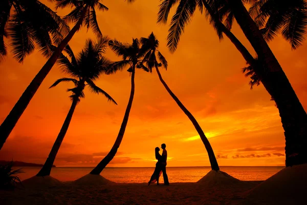 Paar küsst sich am tropischen Strand mit Palmen und Sonnenuntergang — Stockfoto