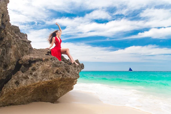 Joven hermosa mujer sola en vestido rojo sentado en la roca en el fondo del mar —  Fotos de Stock