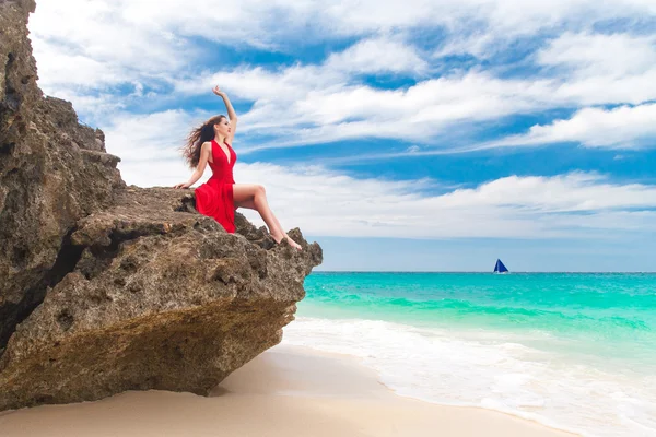 Joven hermosa mujer sola en vestido rojo sentado en la roca en —  Fotos de Stock