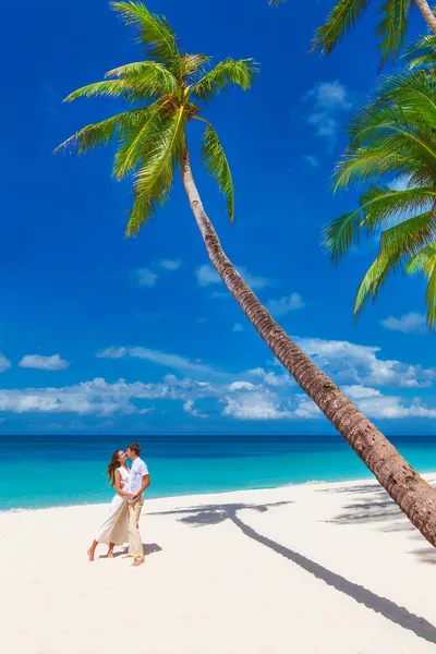 Mladí milující šťastný pár líbání na tropické pláži s palm t — Stock fotografie