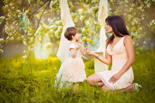 Mujer feliz y niño en el floreciente jardín de primavera.Niño kissi —  Fotos de Stock