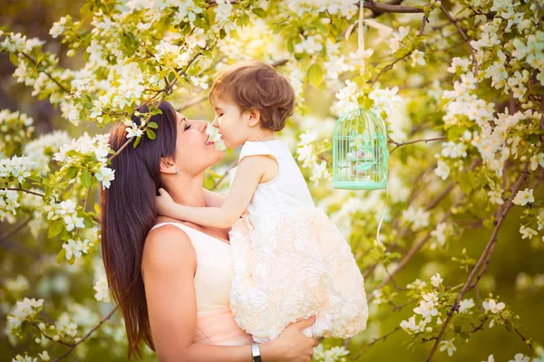 Happy woman and child in the blooming spring garden.Child kissi — Stock Photo, Image