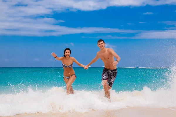 Happy couple running on the beach — Stock Photo, Image