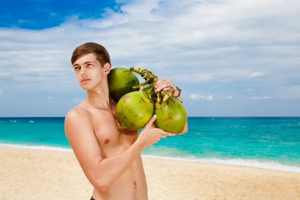 Happy handsome young male beach holding coconuts under the sun o — Stock Photo, Image