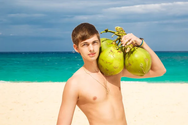 Happy handsome young male beach smiling at camera holding coconu — Stock Photo, Image