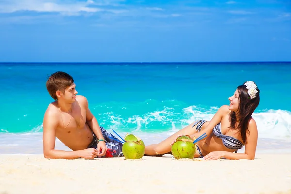 Jonge liefdevolle gelukkige paar op tropisch strand, met kokosnoten — Stockfoto