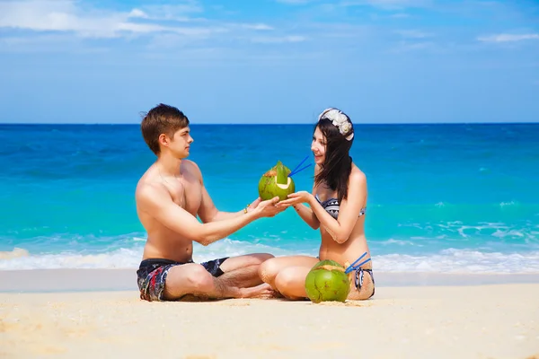 Young loving happy couple on tropical beach, with coconuts — Stock Photo, Image