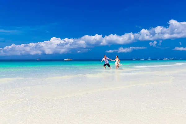 Жених и невеста бегут по тропическому пляжу — стоковое фото