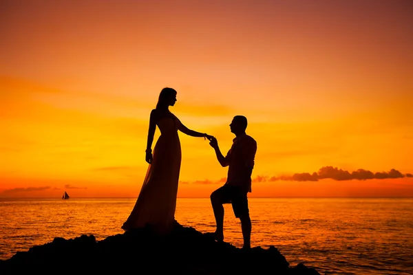 Bride and groom on a tropical beach with the sunset in the backg — Stock Photo, Image