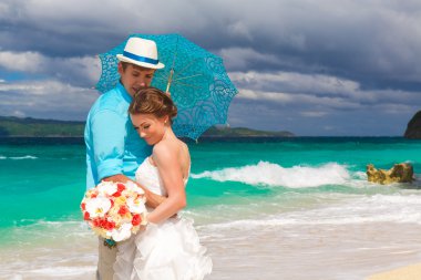 Happy bride and groom with blue umbrella and wedding bouquets on clipart