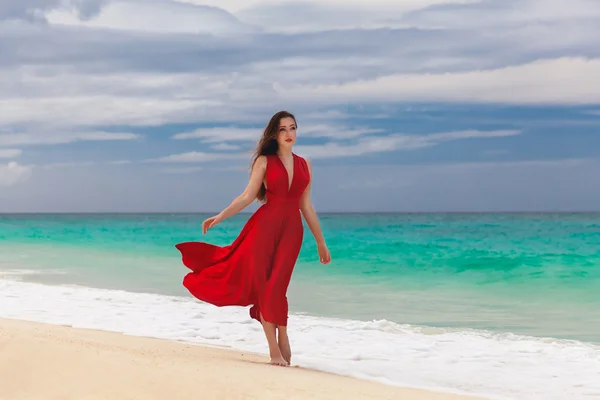 Красивая женщина в красном платье, стоящая на берегу моря — стоковое фото