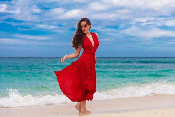一件红色的连衣裙站在海岸上美丽的女人 — Φωτογραφία Αρχείου