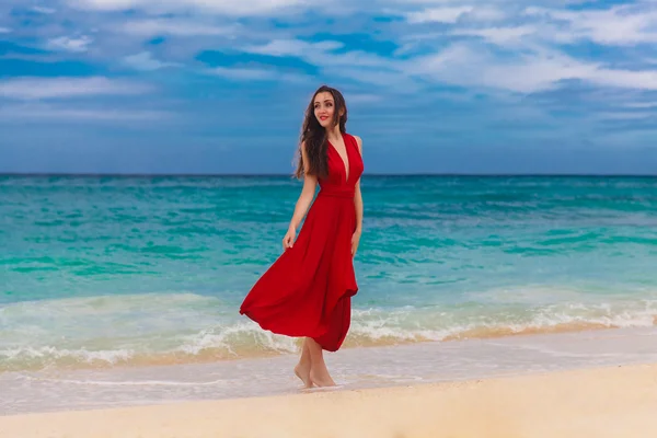 Улыбающаяся красивая женщина в красном платье, стоящая на морских бухтах — стоковое фото