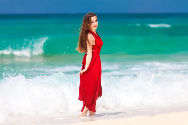 Красивая женщина в красном платье, стоящая на берегу тропического моря — стоковое фото