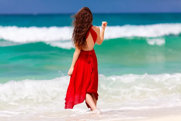 Beautiful woman in a red dress  standing on the tropical sea coa — Stock Photo, Image