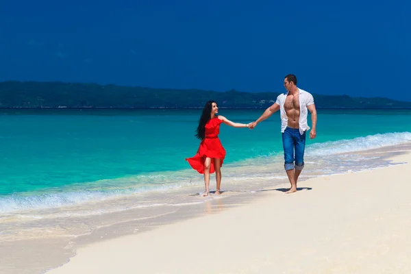 Young loving couple walk through the tropical beach — Stockfoto