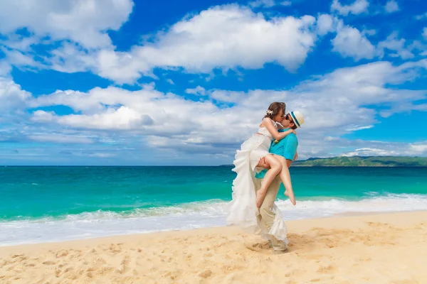 Bride and groom kiss on a tropical beach — Stock Photo, Image
