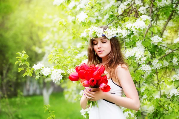 Πορτρέτο του μια όμορφη νεαρή γυναίκα σε ένα στεφάνι από άνοιξη λουλούδι — Φωτογραφία Αρχείου