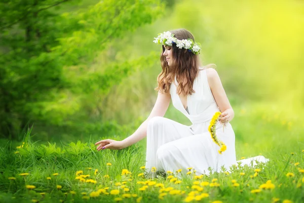 Imagem de mulher bonita em um vestido branco tece guirlanda de dande — Fotografia de Stock