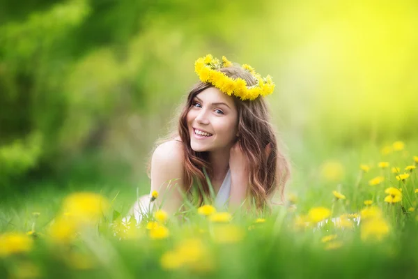 Imagem de mulher bonita deitada no campo de dentes-de-leão, feliz che — Fotografia de Stock