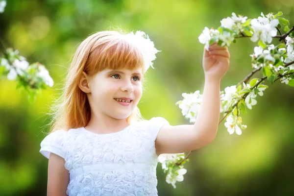 Glad liten tjej att ha kul i den blommande våren trädgård — Stockfoto