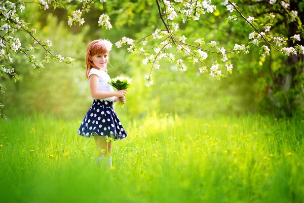 Menina feliz com um buquê de lírios do vale ter — Fotografia de Stock